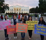 students holding posters in front of white house
