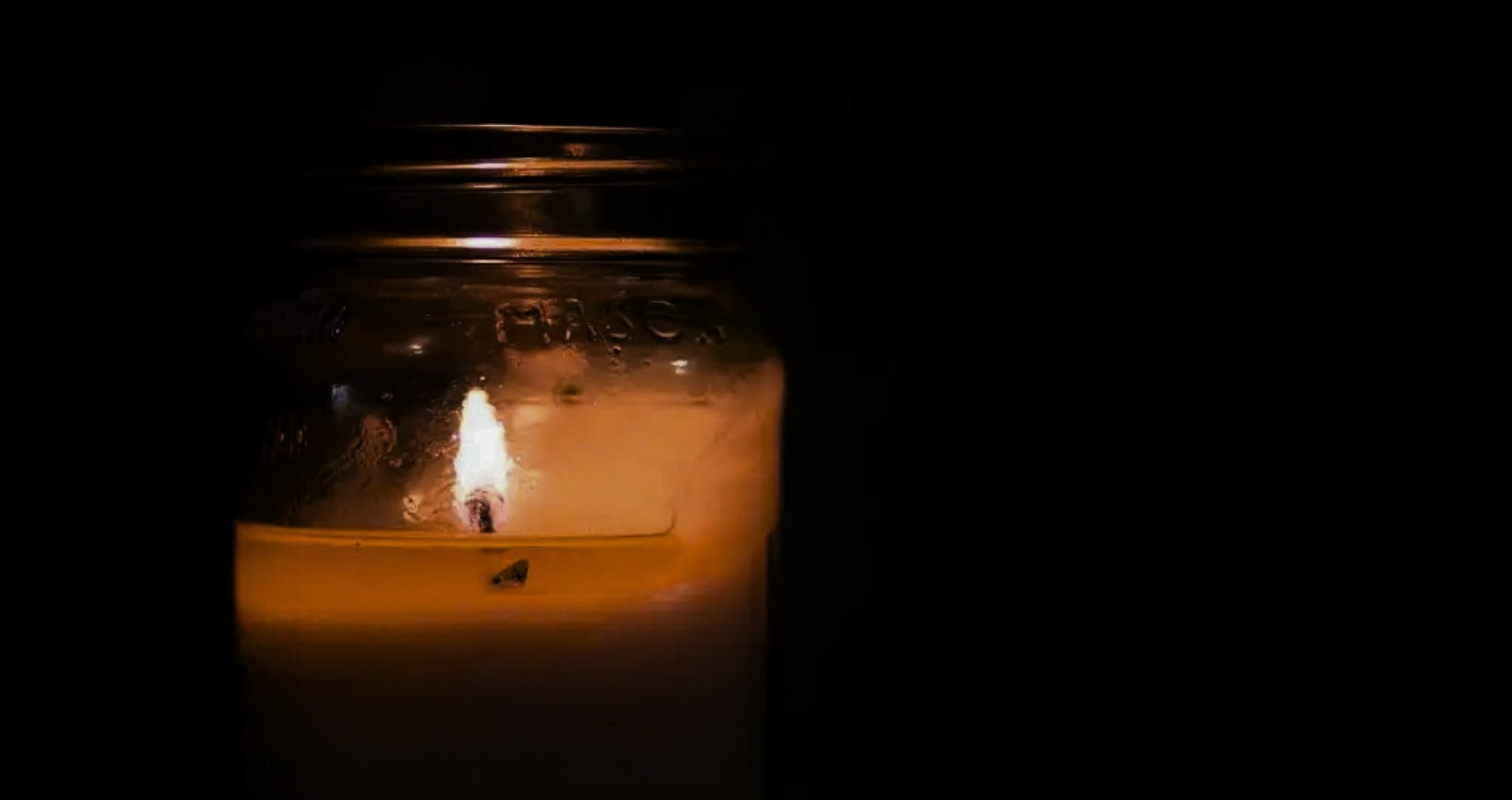 A single candle is lit in darkness.